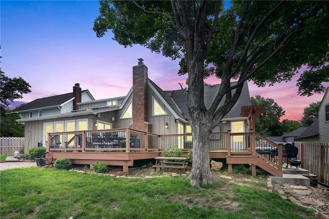 10136 Barton St, Overland Park, KS 66214 - back of house at dusk with board and batten siding, a deck, and a chimney