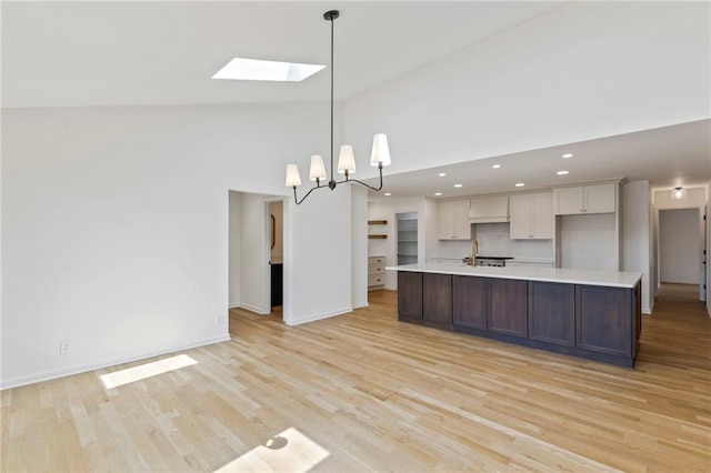 10136 Barton St, Overland Park, KS 66214 - kitchen with light countertops, a skylight, high vaulted ceiling, light wood-type flooring, and white cabinetry