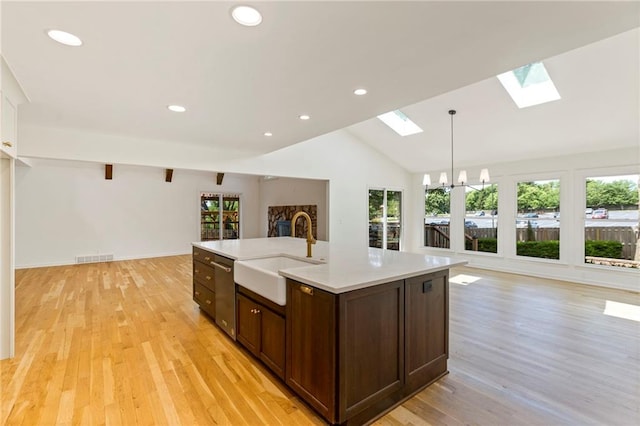 10136 Barton St, Overland Park, KS 66214 - kitchen featuring a skylight, stainless steel dishwasher, open floor plan, light countertops, and light wood-type flooring