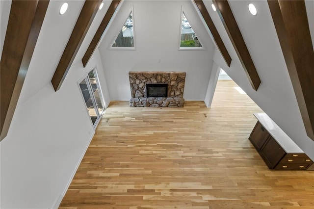 10136 Barton St, Overland Park, KS 66214 - unfurnished living room with a stone fireplace, light wood-style floors, beam ceiling, and high vaulted ceiling