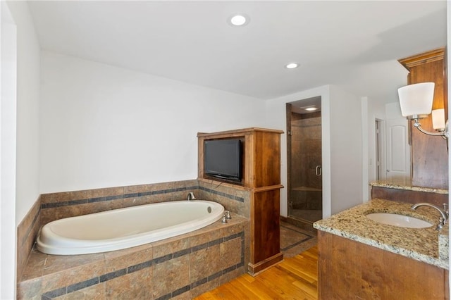 10136 Barton St, Overland Park, KS 66214 - bathroom featuring vanity, a bath, a stall shower, wood finished floors, and recessed lighting