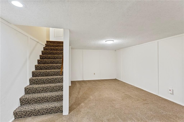 10136 Barton St, Overland Park, KS 66214 - finished basement featuring stairs, a textured ceiling, and light colored carpet