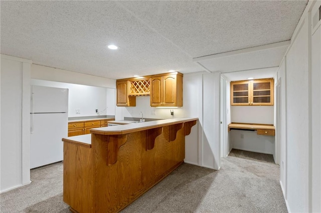 10136 Barton St, Overland Park, KS 66214 - kitchen with freestanding refrigerator, light carpet, a breakfast bar, brown cabinets, and recessed lighting