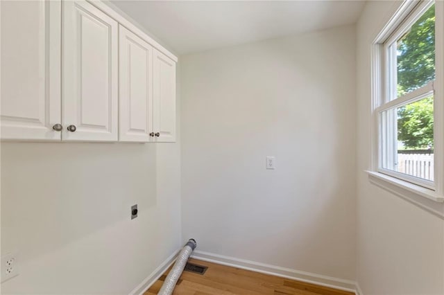 10136 Barton St, Overland Park, KS 66214 - laundry area featuring electric dryer hookup, cabinet space, and light wood-type flooring