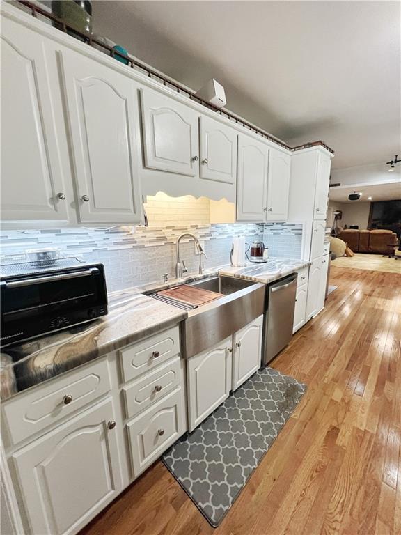 3342 Duncan St, Saint Joseph, MO 64507 - kitchen featuring dishwasher, white cabinetry, light wood-style floors, tasteful backsplash, and light stone counters