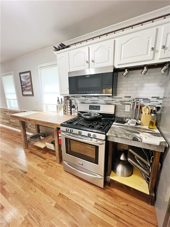 3342 Duncan St, Saint Joseph, MO 64507 - kitchen with appliances with stainless steel finishes, ornamental molding, white cabinets, backsplash, and light wood-style floors