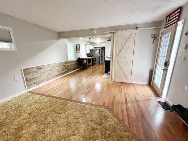 3342 Duncan St, Saint Joseph, MO 64507 - unfurnished living room featuring a barn door, light wood-style floors, and crown molding