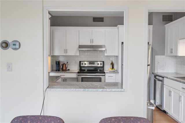 333 W Meyer Blvd # 212, Kansas City, MO 64113 - kitchen with appliances with stainless steel finishes, under cabinet range hood, white cabinetry, and tasteful backsplash
