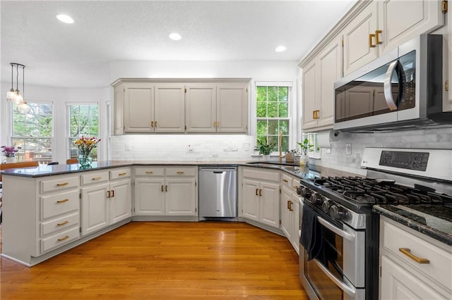14712 Woodward St, Overland Park, KS 66223 - kitchen with appliances with stainless steel finishes, a peninsula, healthy amount of natural light, light wood finished floors, and recessed lighting