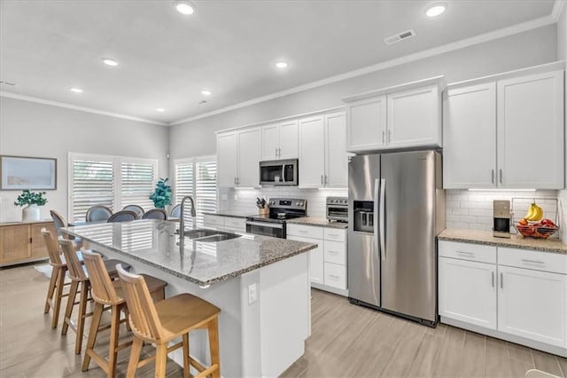 21404 W 47th Ter, Shawnee, KS 66218 - kitchen with appliances with stainless steel finishes, a kitchen breakfast bar, a center island with sink, crown molding, and white cabinetry