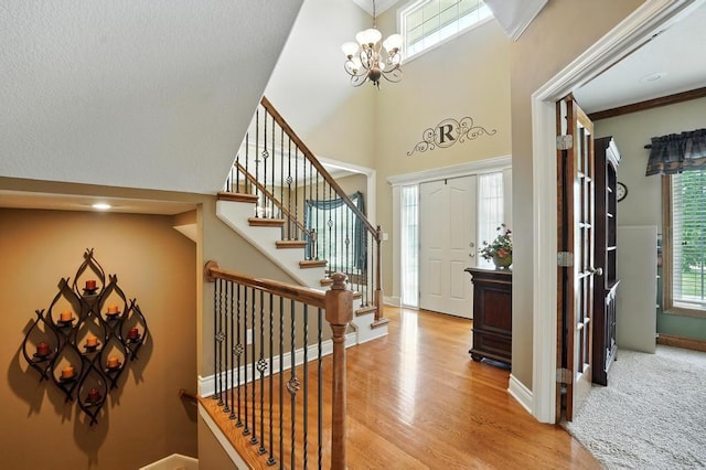 2312 NE Sweet Water Dr, Lees Summit, MO 64086 - entryway with a towering ceiling, stairs, light wood finished floors, and a chandelier
