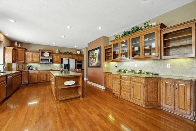 2312 NE Sweet Water Dr, Lees Summit, MO 64086 - kitchen with open shelves, appliances with stainless steel finishes, wood finished floors, tasteful backsplash, and brown cabinets