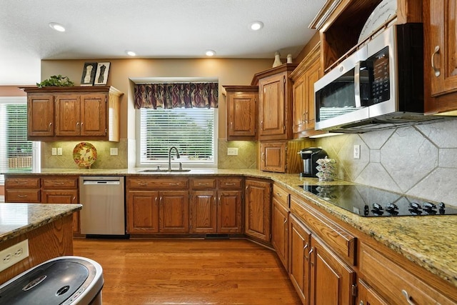 2312 NE Sweet Water Dr, Lees Summit, MO 64086 - kitchen featuring appliances with stainless steel finishes, healthy amount of natural light, light wood finished floors, brown cabinets, and recessed lighting