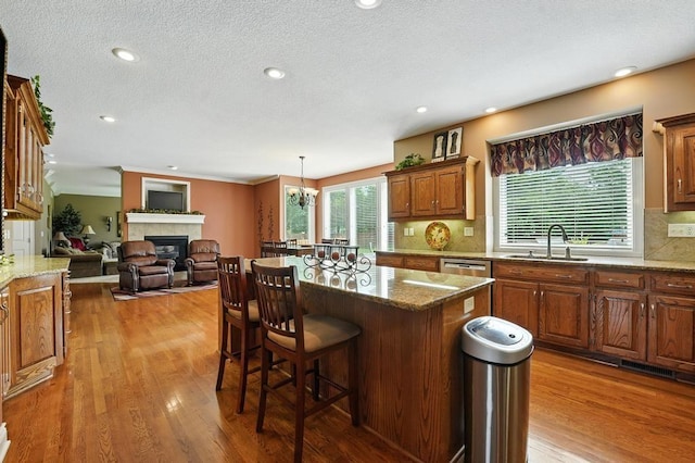 2312 NE Sweet Water Dr, Lees Summit, MO 64086 - kitchen featuring a kitchen breakfast bar, wood finished floors, tasteful backsplash, a tiled fireplace, and a textured ceiling