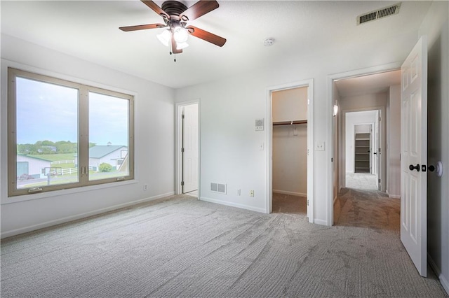 26528-23.09 S Metcalf Rd, Louisburg, KS 66053 - unfurnished bedroom featuring light colored carpet, a walk in closet, a closet, and ceiling fan