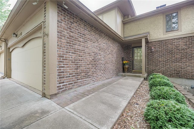 10902 W 96th Ter, Overland Park, KS 66214 - property entrance with stucco siding, driveway, brick siding, and an attached garage