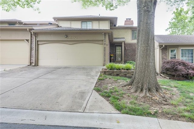 10902 W 96th Ter, Overland Park, KS 66214 - view of front of house with an attached garage, concrete driveway, a chimney, brick siding, and stucco siding