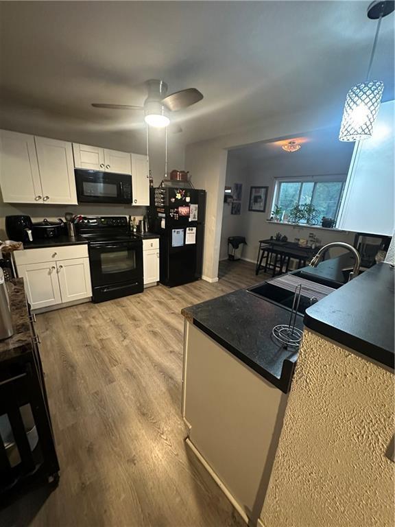 3823 Ruby Ave, Kansas City, KS 66106 - kitchen featuring black appliances, white cabinets, dark countertops, and light wood finished floors