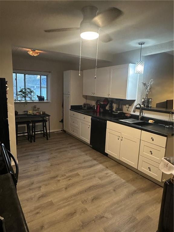 3823 Ruby Ave, Kansas City, KS 66106 - kitchen with black dishwasher, dark countertops, light wood-style flooring, and white cabinetry