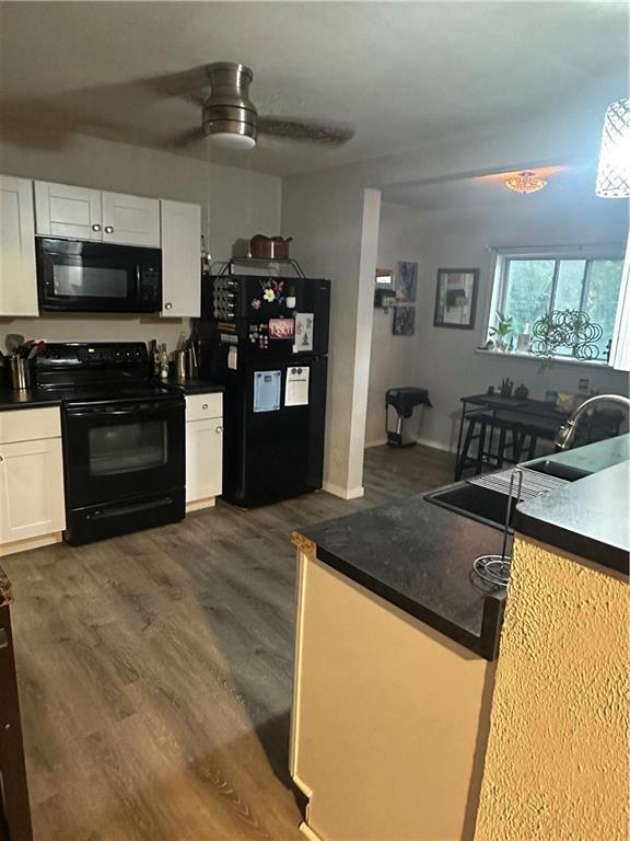 3823 Ruby Ave, Kansas City, KS 66106 - kitchen with black appliances, white cabinetry, dark wood-style flooring, and dark countertops