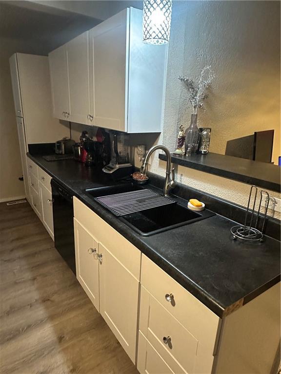 3823 Ruby Ave, Kansas City, KS 66106 - kitchen featuring black dishwasher, dark wood-style floors, white cabinets, and dark countertops