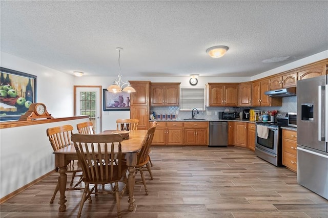 606 S Thornton St, Richmond, MO 64085 - kitchen featuring stainless steel appliances, under cabinet range hood, light wood-style flooring, and a textured ceiling
