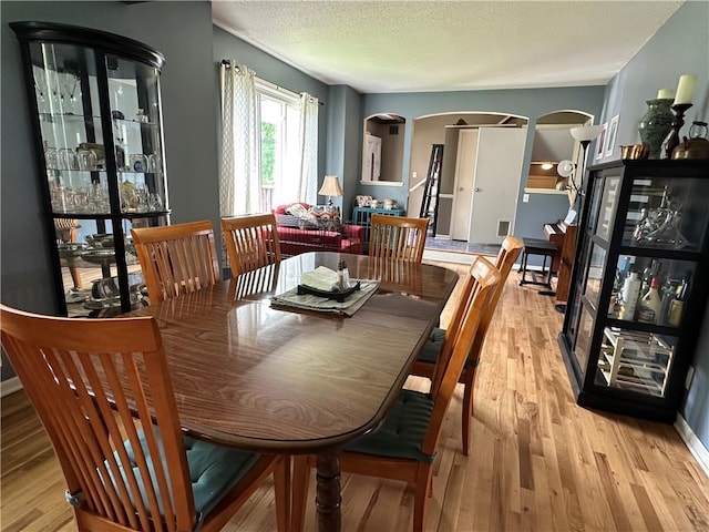 8708 W 92nd St, Overland Park, KS 66212 - dining room with arched walkways, light wood-style floors, and a textured ceiling