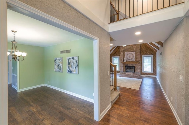 6919 Albervan St, Shawnee, KS 66216 - unfurnished living room with a chandelier, wood finished floors, stairs, a brick fireplace, and a textured wall
