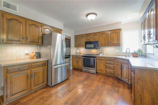 6919 Albervan St, Shawnee, KS 66216 - kitchen featuring stainless steel appliances, brown cabinets, dark wood-style flooring, light countertops, and recessed lighting