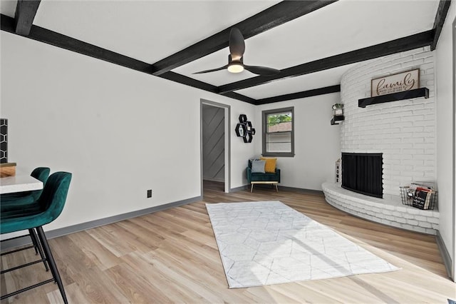 1208 SW Speas Dr, Blue Springs, MO 64014 - living room featuring beamed ceiling, ceiling fan, wood finished floors, and a fireplace