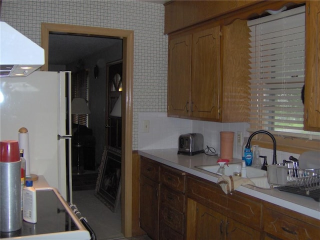 3016 S Northern Blvd, Independence, MO 64052 - kitchen with freestanding refrigerator, ventilation hood, light countertops, backsplash, and brown cabinets