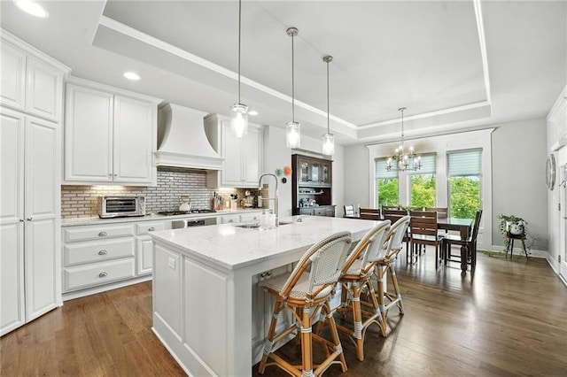 27181 W 100th Ter, Olathe, KS 66061 - kitchen with a raised ceiling, premium range hood, tasteful backsplash, white cabinets, and recessed lighting