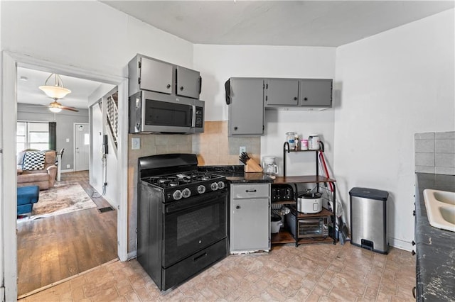 218 N 25th St, Kansas City, KS 66102 - kitchen with black range with gas cooktop, stainless steel microwave, gray cabinets, dark countertops, and a ceiling fan