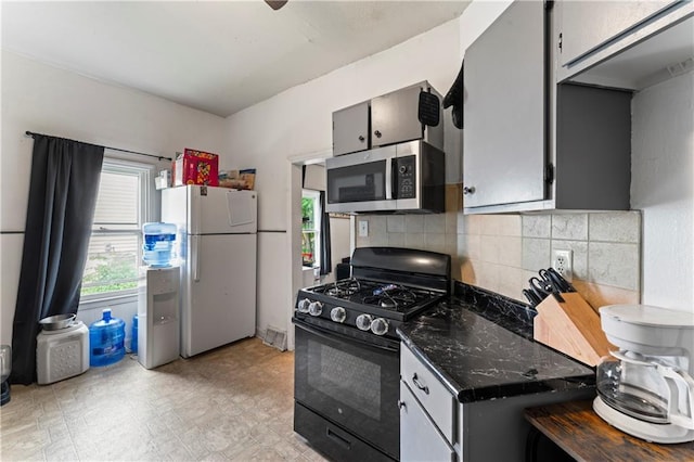 218 N 25th St, Kansas City, KS 66102 - kitchen featuring stainless steel microwave, gas stove, freestanding refrigerator, decorative backsplash, and dark stone counters