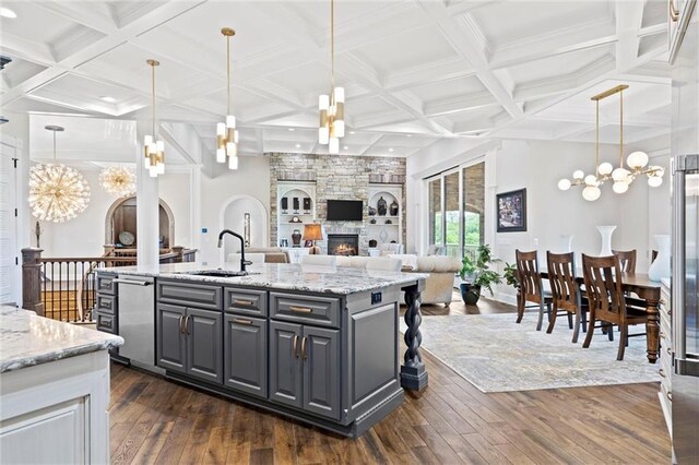 18405 371st Hwy, Platte City, MO 64079 - kitchen featuring stainless steel dishwasher, dark wood-style floors, a fireplace, a kitchen island with sink, and gray cabinetry