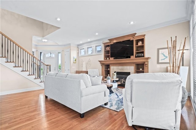 4204 SW Duck Pond Dr, Lees Summit, MO 64082 - living area with crown molding, light wood-style floors, stairs, a tiled fireplace, and recessed lighting