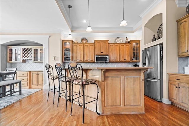4204 SW Duck Pond Dr, Lees Summit, MO 64082 - kitchen featuring appliances with stainless steel finishes, tasteful backsplash, a kitchen bar, brown cabinetry, and light wood-type flooring