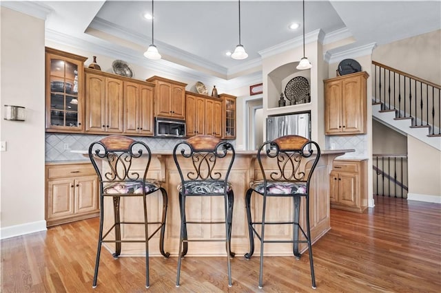 4204 SW Duck Pond Dr, Lees Summit, MO 64082 - kitchen featuring stainless steel appliances, a kitchen bar, light wood-style flooring, tasteful backsplash, and ornamental molding