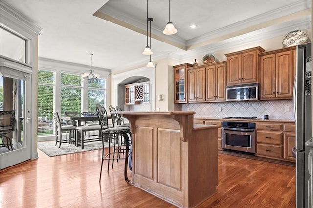 4204 SW Duck Pond Dr, Lees Summit, MO 64082 - kitchen featuring stainless steel appliances, a kitchen bar, crown molding, brown cabinetry, and dark wood-style floors