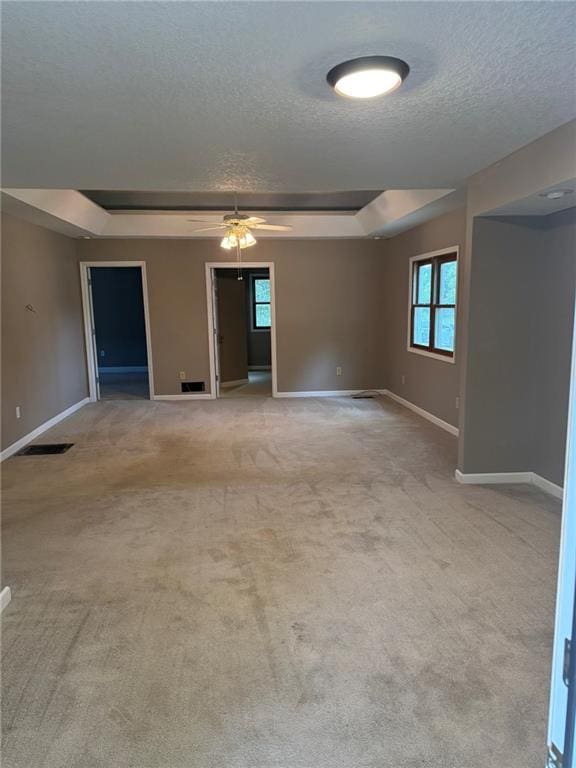 915 Des Moines St, Burlington, KS 66839 - empty room featuring a textured ceiling, a raised ceiling, ceiling fan, and carpet flooring
