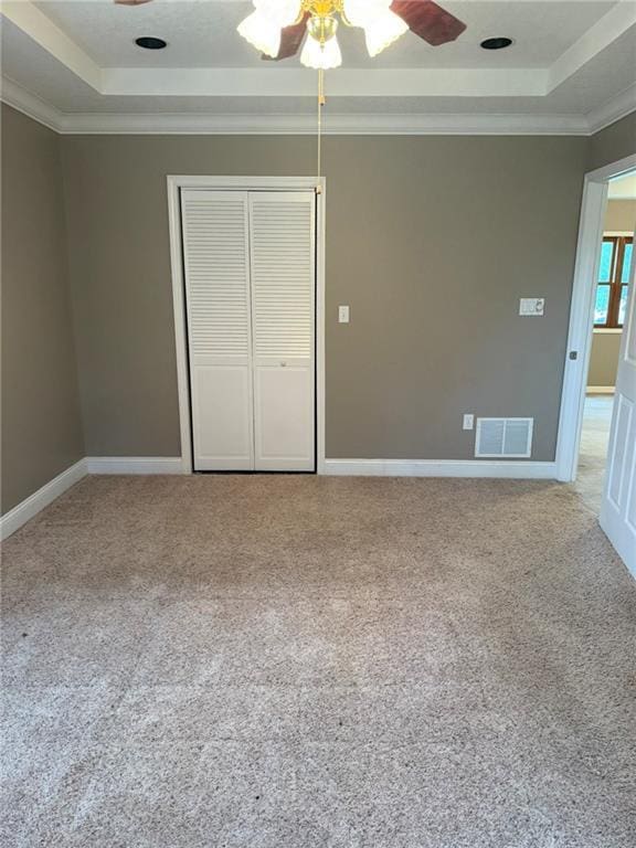 915 Des Moines St, Burlington, KS 66839 - unfurnished bedroom with a tray ceiling, ornamental molding, a closet, light colored carpet, and a ceiling fan