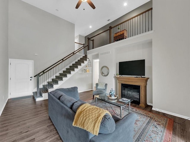 21818 W 123rd Ter, Olathe, KS 66061 - living area with stairway, a high ceiling, a ceiling fan, wood finished floors, and a glass covered fireplace