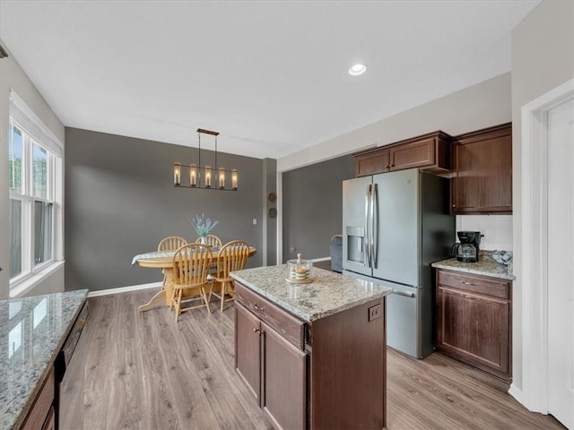 21818 W 123rd Ter, Olathe, KS 66061 - kitchen with stainless steel appliances, light wood finished floors, hanging light fixtures, light stone countertops, and a chandelier