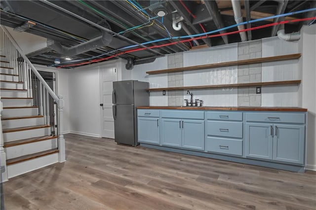 7824 Terrace St, Kansas City, MO 64114 - finished below grade area featuring freestanding refrigerator, stairs, and wood finished floors