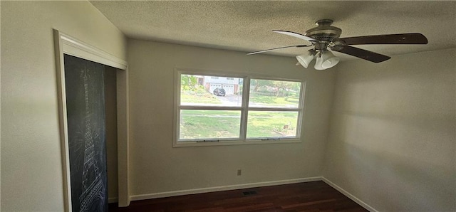 1113 W 27th St, Lawrence, KS 66046 - unfurnished bedroom with dark wood-style floors, a textured ceiling, ceiling fan, and a closet