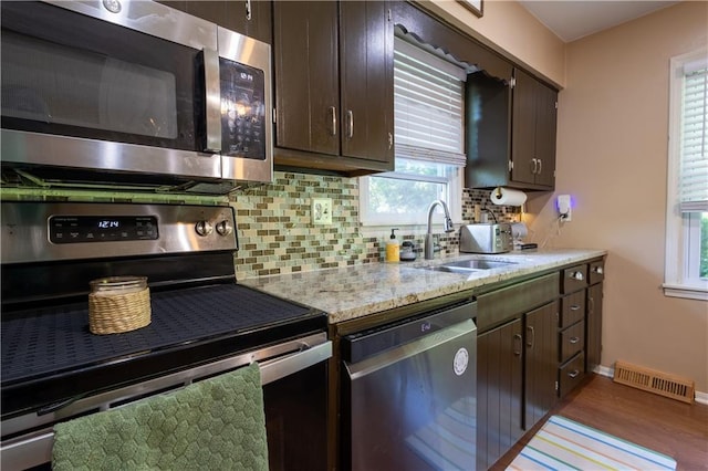 2905 Ajax Rd, Saint Joseph, MO 64503 - kitchen featuring appliances with stainless steel finishes, decorative backsplash, dark brown cabinets, and wood finished floors
