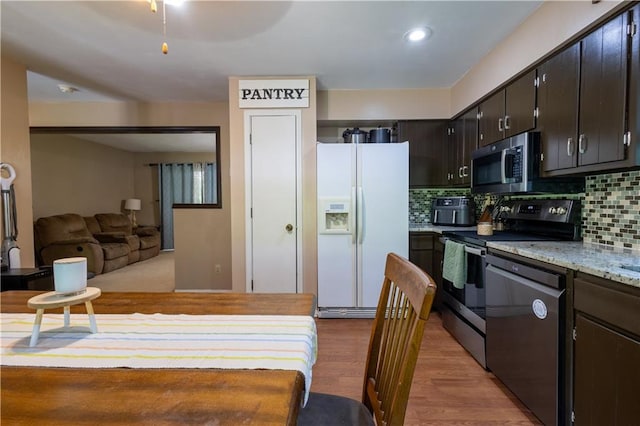 2905 Ajax Rd, Saint Joseph, MO 64503 - kitchen featuring appliances with stainless steel finishes, backsplash, wood finished floors, open floor plan, and light stone countertops