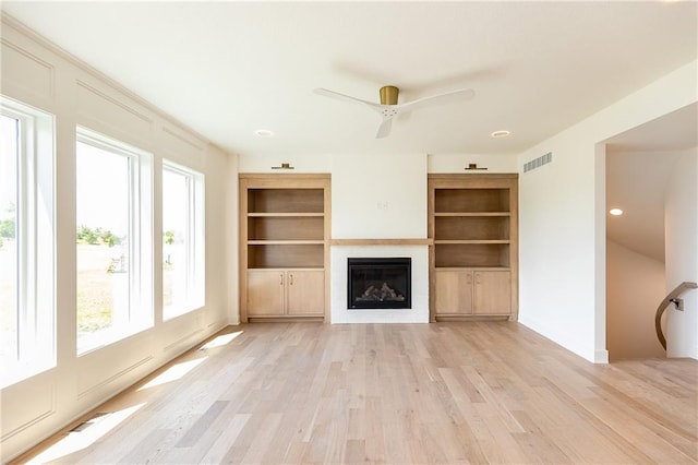 18505 Mohawk Ln, Overland Park, KS 66085 - unfurnished living room featuring a glass covered fireplace, light wood-type flooring, ceiling fan, and built in features