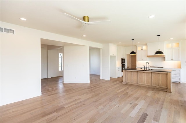 18505 Mohawk Ln, Overland Park, KS 66085 - kitchen featuring stainless steel microwave, backsplash, light wood-style flooring, recessed lighting, and white cabinets