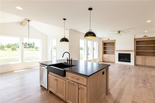 18505 Mohawk Ln, Overland Park, KS 66085 - kitchen featuring stainless steel dishwasher, dark countertops, light wood-type flooring, an island with sink, and a fireplace